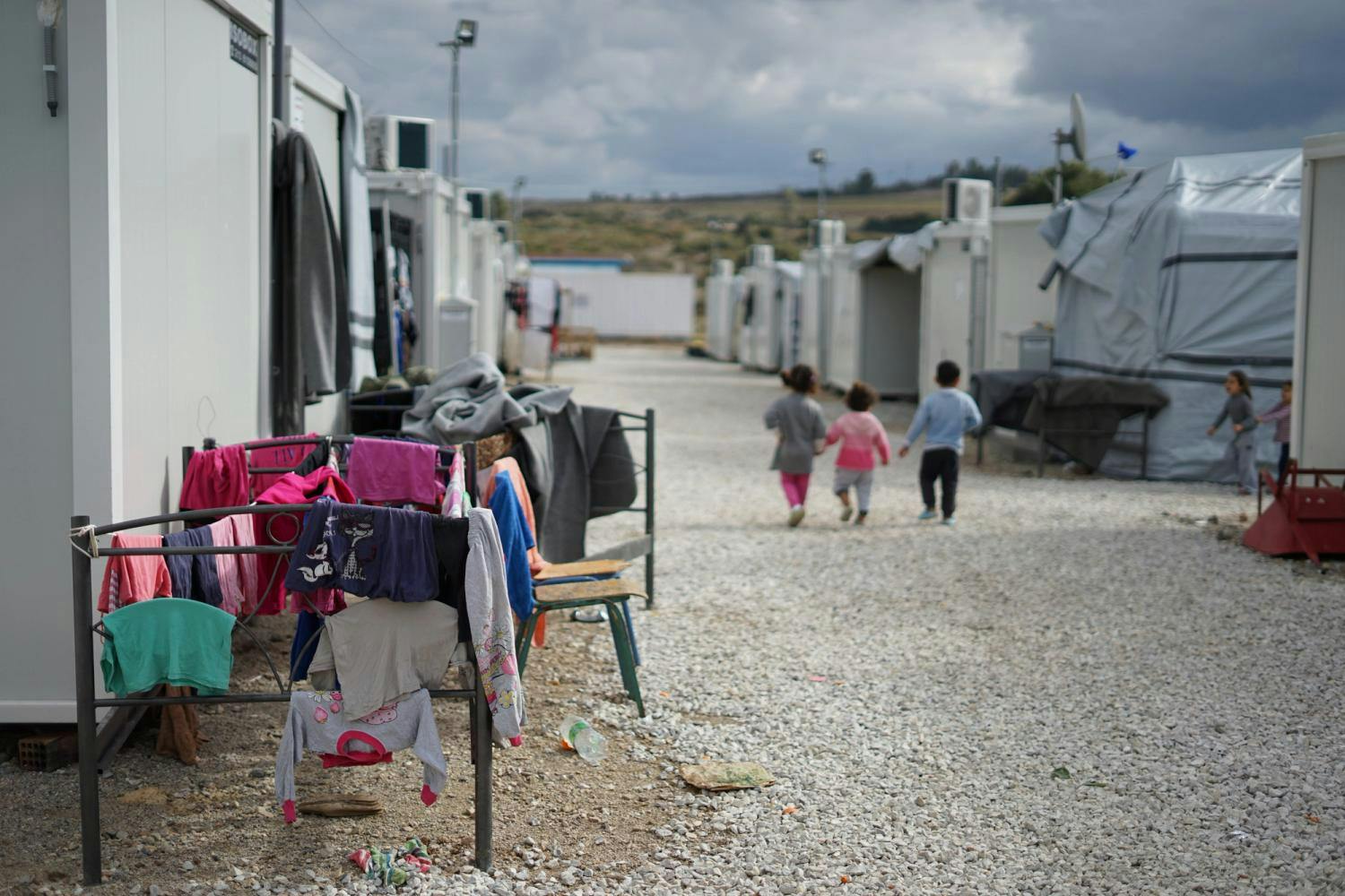 Bilde fra en flyktningleir. Bilde av klær som tørker og noen barn i bakgrunnen 