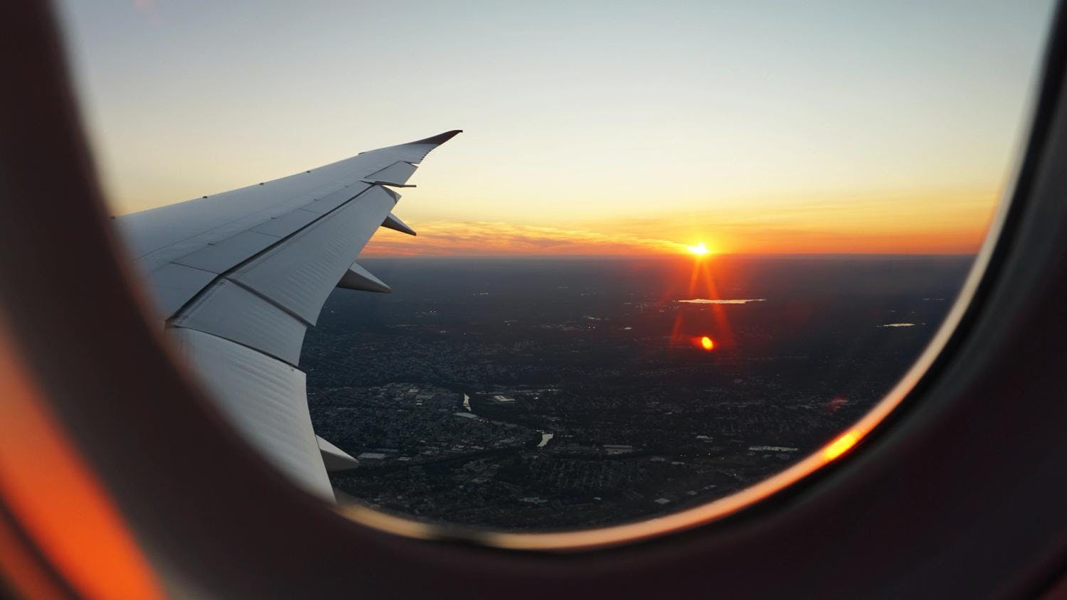 Bilde av et flyvindu med solnedgang i bakgrunnen