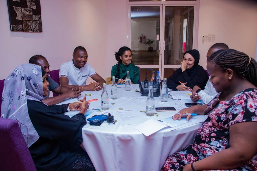 Bilde av deltagere som sitter rundt et bord og diskuterer